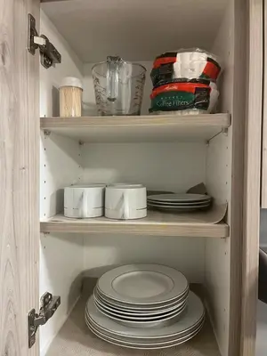 a cupboard filled with plates and dishes in a kitchen at Cozy Basement Near Airport YYC in Calgary