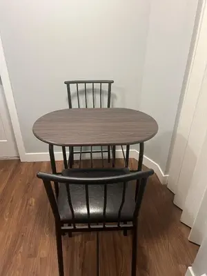 a wooden table and a chair in a room at Cozy Basement Near Airport YYC in Calgary