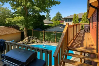 a deck with a pool and a grill next to a house at Quaint Attic Suite with Heated Pool Year-Round in Victoria