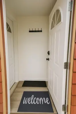 a hallway with a welcome mat in front of a door at Quaint Attic Suite with Heated Pool Year-Round in Victoria