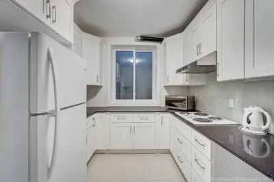 a white kitchen with white cabinets and a white refrigerator at D Peaceful Suite in West Vancouver