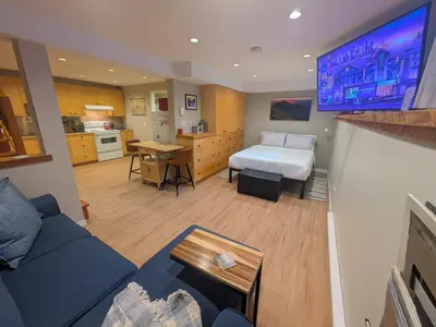 a living room with a bed and a kitchen with at Fresh Studio Apartment in Central Rossland in Rossland