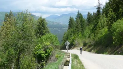 a person riding a bike down a road at Fresh Studio Apartment in Central Rossland in Rossland