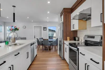 a kitchen with white cabinets and a dining room at Your Pleasant stay in 3 bedroom House in Saddle-Ridge in Calgary