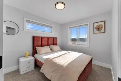 a bedroom with a large bed and two windows at Your Pleasant stay in 3 bedroom House in Saddle-Ridge in Calgary