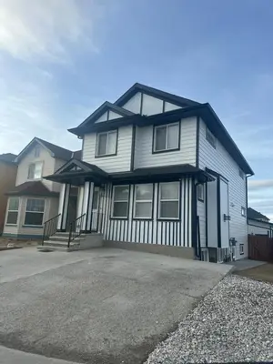 a white house with a black roof at Your Pleasant stay in 3 bedroom House in Saddle-Ridge in Calgary