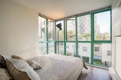 a bedroom with a bed and a large window at Yaletown Gorgeous Unit Steps from the Beach in Vancouver