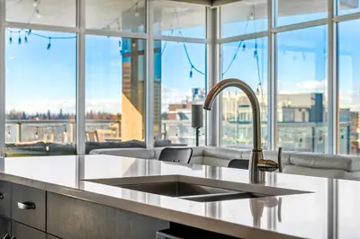 a kitchen with a sink and a large window at Urban Oasis - 2BR Condo Downtown Large Balcony in Calgary