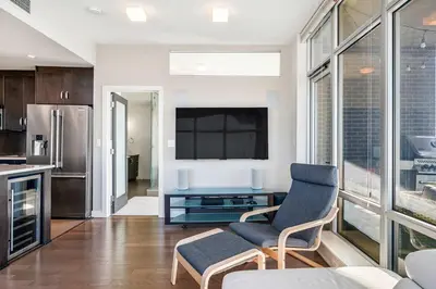 a kitchen and living room with a tv and a couch at Urban Oasis - 2BR Condo Downtown Large Balcony in Calgary