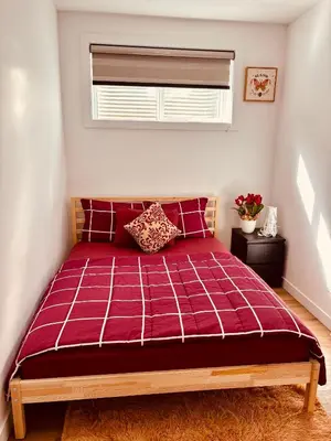 a bedroom with a red bed with a window at Charming Stay & Cozy Retreat by Bansari Homes in Edmonton- YEG in Edmonton