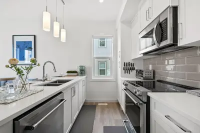 a kitchen with white cabinets and stainless steel appliances at Luxury Aspen 2BR Home with Double Garage Car Parking in Calgary