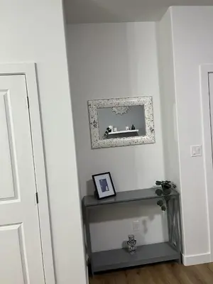 a hallway with a table and a picture on the wall at Elegant 3BD Home in Beaumont, Double Garage in Nisku