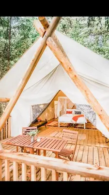 a tent with a wooden floor and a table at Haida Gwaii Glamping in Tlell