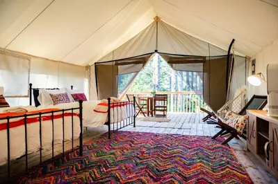 a tent with a bed and a table and chairs at Haida Gwaii Glamping in Tlell