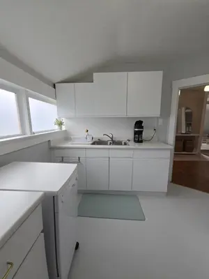 a white kitchen with white cabinets and a sink at Two bedroom coastal retreat in Victoria