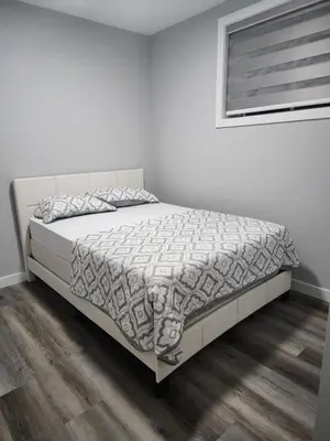 a bedroom with a bed with a white bedspread at lovely 2bed & 1 Bath Basement Suite for 4 guests in Calgary