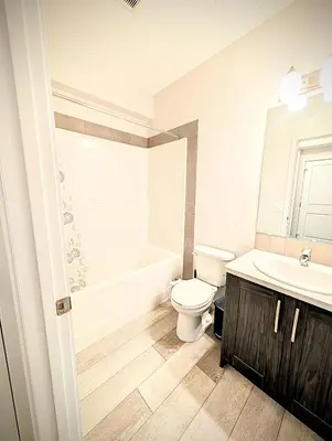 a bathroom with a toilet and a sink and a tub at Luxury Modern 2-Bedroom Suite in Airdrie