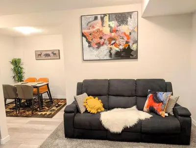 a black couch sitting in a living room with a table at Luxury Modern 2-Bedroom Suite in Airdrie