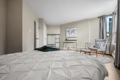 a bedroom with a large bed and a chair at Winter Prices Reduced for Stylish Condo & Easy to Mountains ! in Calgary