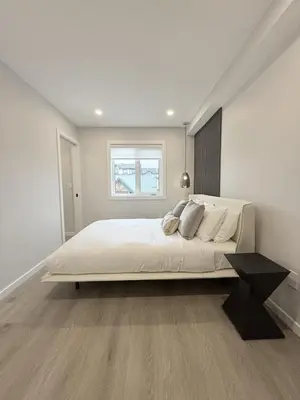 a white bedroom with a large bed with a window at Memory Lodge in Canmore