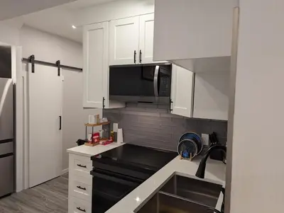 a kitchen with white cabinets and a black counter top at MIAT Apartment in Calgary