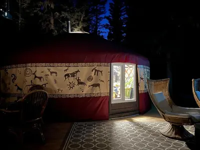a yurt with a door and two chairs and a table at Shanti Yurt with private hot tub in Bragg Creek in Bragg Creek