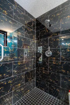 a bathroom with a black tiled wall with gold designs at Shanti Yurt with private hot tub in Bragg Creek in Bragg Creek