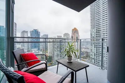 a balcony with a table and chairs and a view of a city at Modern Downtown Apartment with Water Views in Vancouver