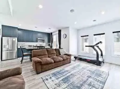 a living room with a brown couch and a kitchen at Cozy two bed apartment in Calgary