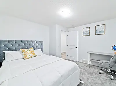 a white bedroom with a large bed and a desk at Cozy two bed apartment in Calgary