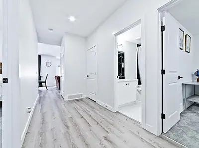 a white room with a hallway with white walls and a mirror at Cozy two bed apartment in Calgary