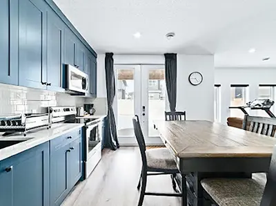 a kitchen with blue cabinets and a table with chairs at Cozy two bed apartment in Calgary