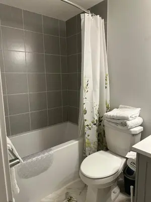 a bathroom with a toilet and a shower curtain at The Modern Nest-one bedroom basement suite in Calgary