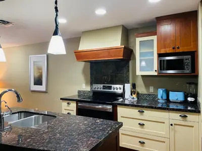 a kitchen with a sink and a stove top oven at Solara Getaway 2BR Condo with Pool - Hot Tub - Gym - Spa in Canmore