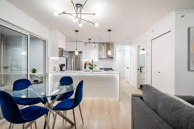 a kitchen and living room with a glass table and blue chairs at Gorgeous Downtown Unit with City Views in Vancouver