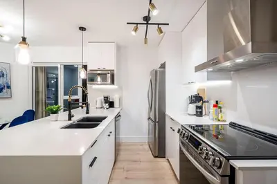 a kitchen with white counters and a sink and a refrigerator at Gorgeous Downtown Unit with City Views in Vancouver