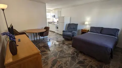 a bedroom with a bed and a table and a kitchen at Deerview Lodge & Cabins - Princeton BC in Princeton