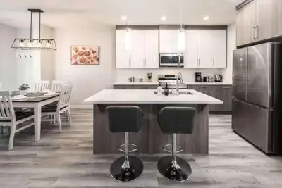 a kitchen with a kitchen island with chairs and a table at Group Stay, Sleeps 16! Near Downtown - 6BR Full Duplex, 2 Kitchens! FREE Banff Pass in Calgary