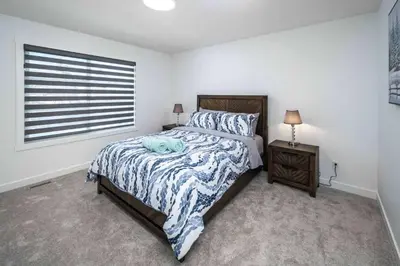 a bedroom with a large bed and a window at Group Stay, Sleeps 16! Near Downtown - 6BR Full Duplex, 2 Kitchens! FREE Banff Pass in Calgary