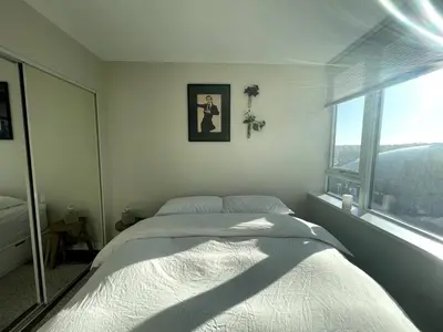 a bedroom with a bed and a large window at Downtown Apartment in Vancouver