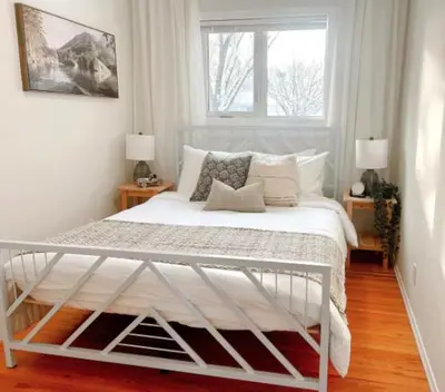 a white bed in a bedroom with a window at Modern 3BR Near Airport & DT in Calgary