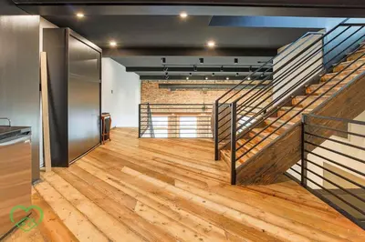 an empty room with a staircase and wooden floors at Downtown Loft with Rooftop Hot Tub by StayIn in Fernie