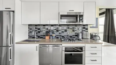 a kitchen with white cabinets and stainless steel appliances at Executive Sky LUX - 2 BD 2BA Views Pool Patio & Gym in Calgary