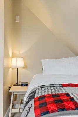 a bedroom with a bed and a table with a lamp at Lake Vibes 3 BD 1 BA Cottage steps from the Lake in Lacombe