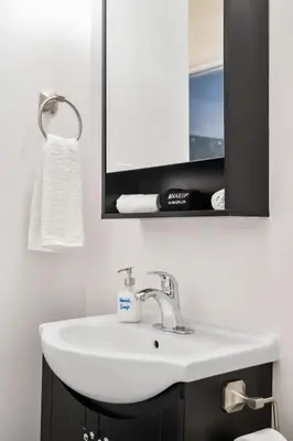 a bathroom with a white sink and a mirror at Eminence Sleek Studio City View in Edmonton