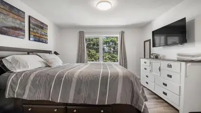 a bedroom with a bed with a dresser and a window at Winston Suite 2BR 1BA - Carriage Suite with Garage in Calgary