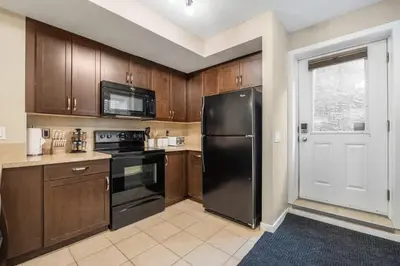 a kitchen with wooden cabinets and a black refrigerator at The Trenta - 4BD 3BA 2 Kitchen Stunner in Calgary