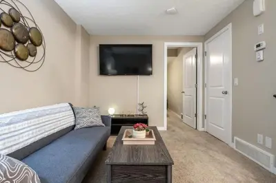 a living room with a couch and a tv on the wall at The Grande 1BD 1BA - Full Kitchen Guest Suite in Calgary