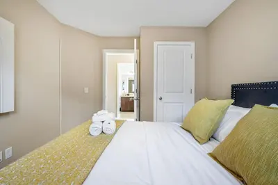 a bedroom with a large white bed with towels on it at The Venti - 3BD 2BA Yard Garage & Upper Suite in Calgary