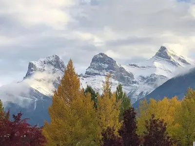 a snow covered mountain range with trees in the foreground at Sun Drenched Escape - 50 Percent Off Apr - May in Canmore
